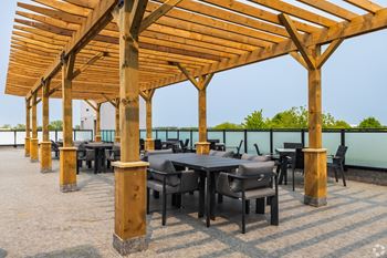 A wooden pergola with tables and chairs is set up on a patio.